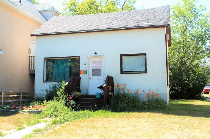 a small white house with a porch and a backdoor